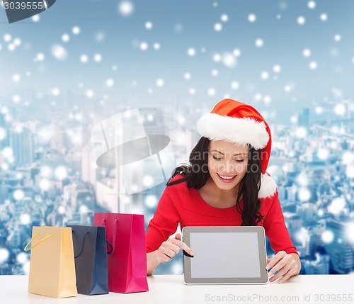 Image of smiling woman with shopping bags and tablet pc