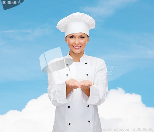 Image of smiling female chef holding something on hands