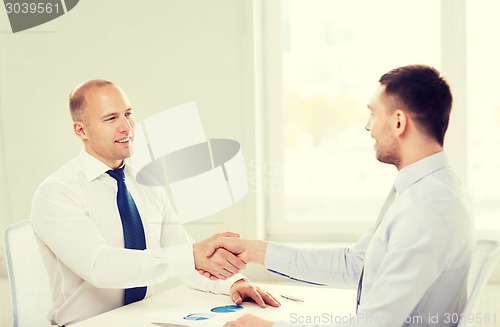 Image of two smiling businessmen shaking hands in office