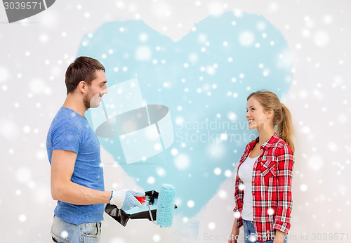 Image of smiling couple painting big heart on wall