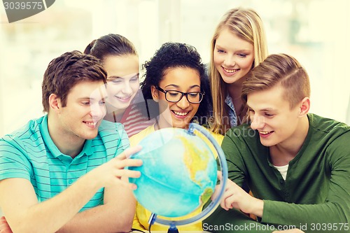 Image of five smiling student looking at globe at school