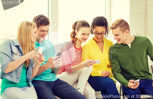 Image of smiling students with smartphone texting at school