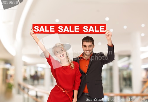 Image of happy young couple with red shopping bags in mall