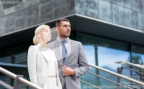 Image of serious businessmen standing over office building