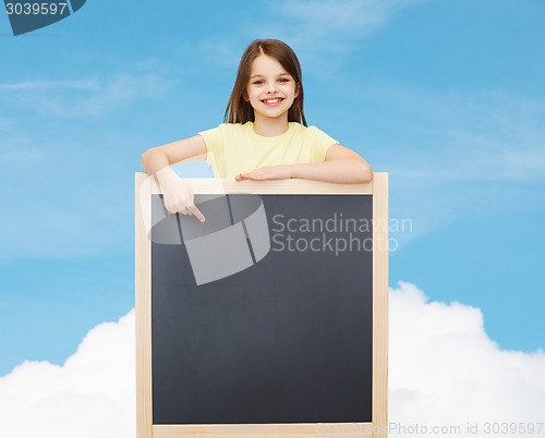 Image of happy little girl pointing finger to blackboard