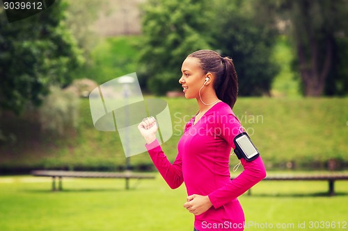 Image of smiling young woman running outdoors