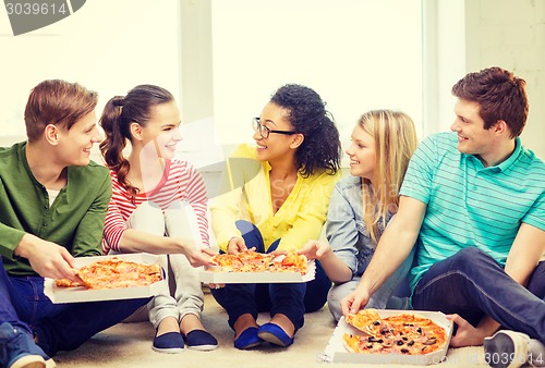 Image of five smiling teenagers eating pizza at home