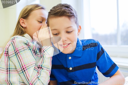 Image of smiling schoolgirl whispering to classmate ear