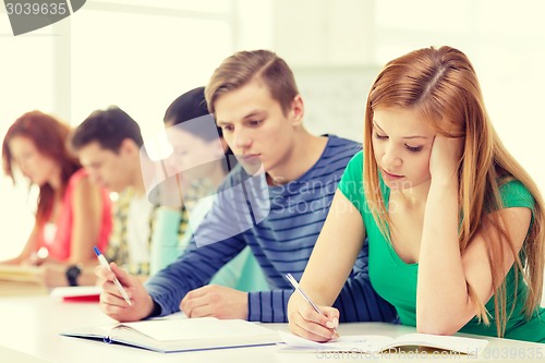 Image of tired students with textbooks and books at school