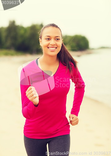 Image of smiling woman running on track outdoors