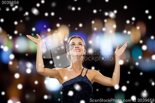 Image of smiling woman raising hands and looking up