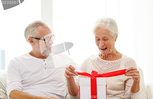 Image of happy senior couple with gift box at home