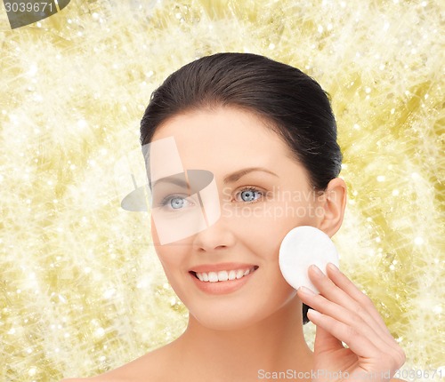 Image of smiling woman cleaning face skin with cotton pad