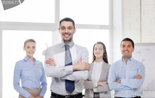 Image of smiling businessman in office with team on back