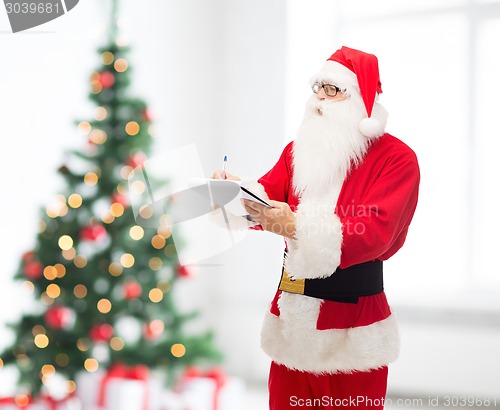 Image of man in costume of santa claus with notepad