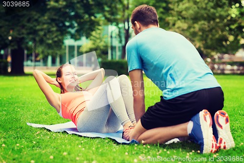 Image of smiling woman doing exercises on mat outdoors