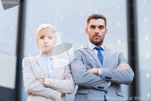 Image of serious businessmen standing over office building