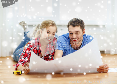 Image of smiling couple with blueprint at home