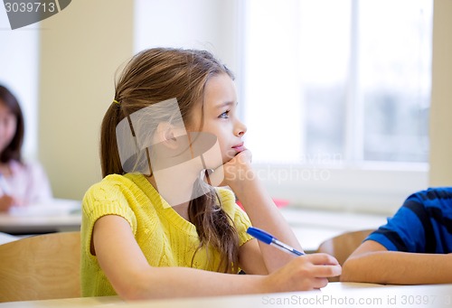 Image of school girl with pen being bored in classroom