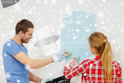 Image of smiling couple with paintbrushes painting wall