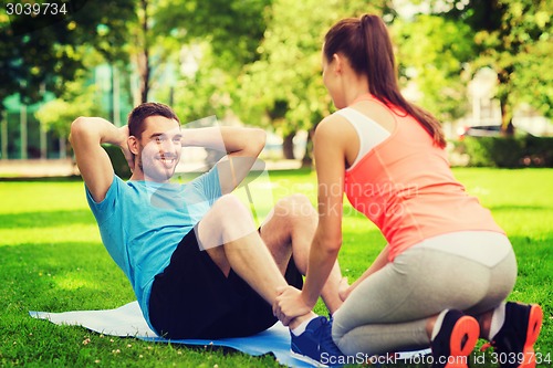Image of smiling man doing exercises on mat outdoors