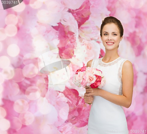 Image of smiling woman in white dress with bouquet of roses