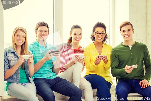 Image of smiling students with smartphone texting at school