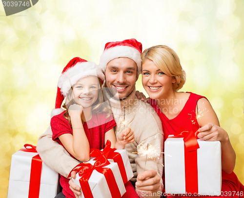 Image of smiling family holding gift boxes and sparkles