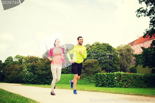 Image of smiling couple running outdoors