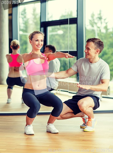 Image of smiling woman with male trainer exercising in gym