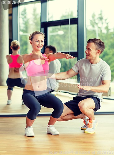 Image of smiling woman with male trainer exercising in gym