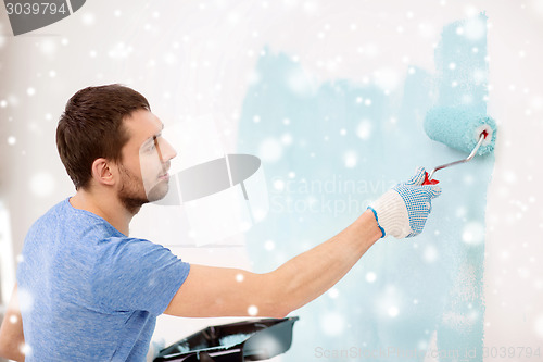 Image of smiling young man with roll and tray painting wall