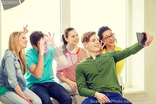 Image of smiling students making picture with tablet pc