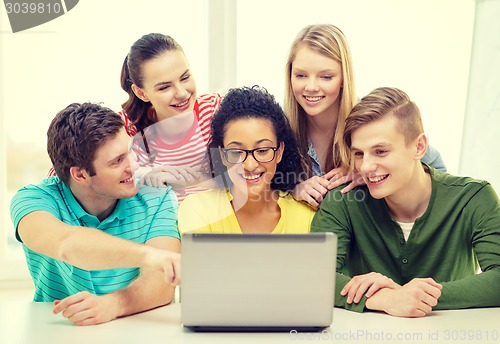 Image of smiling students looking at laptop at school