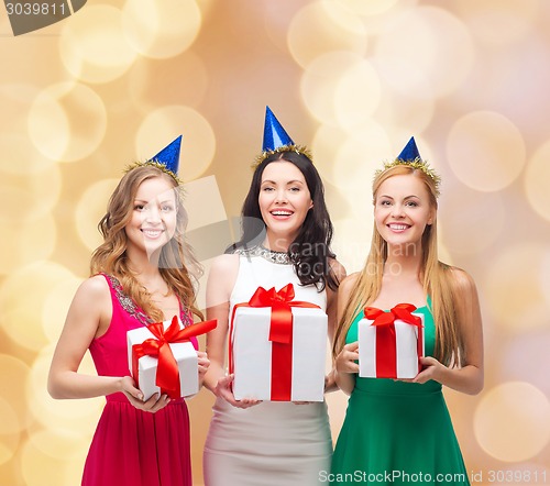 Image of smiling women in party caps with gift boxes