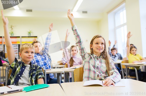 Image of group of school kids raising hands in classroom