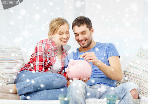 Image of smiling couple with piggybank sitting on sofa