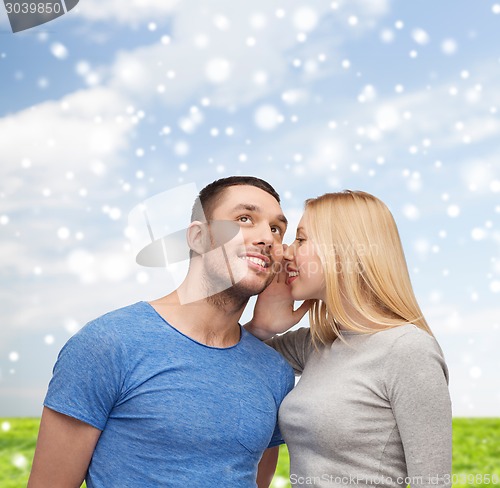 Image of smiling girlfriend telling boyfriend secret