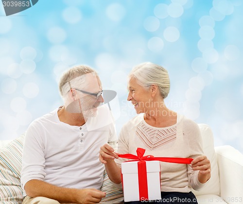 Image of happy senior couple with gift box at home