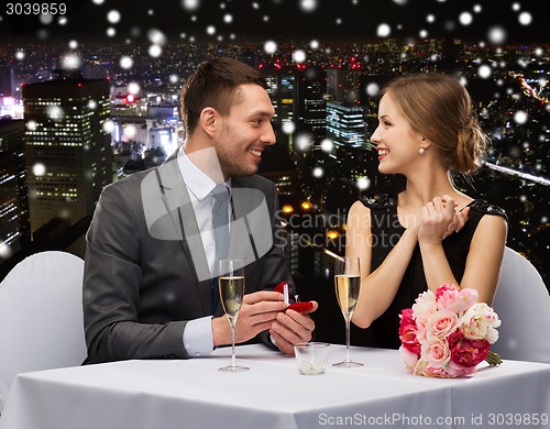 Image of smiling couple with red gift box at restaurant