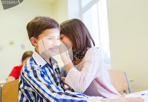 Image of smiling schoolgirl whispering to classmate ear