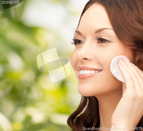Image of smiling woman cleaning face skin with cotton pad