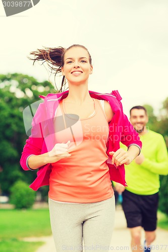 Image of smiling couple running outdoors