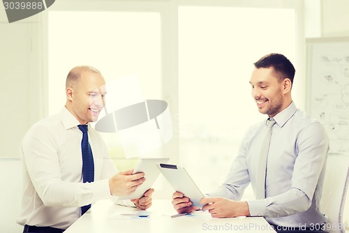 Image of two smiling businessmen with tablet pc in office