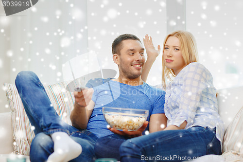 Image of smiling couple watching tv at home