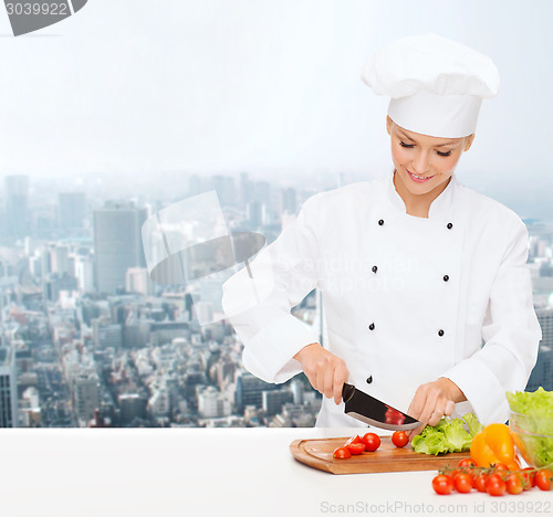 Image of smiling female chef chopping vegetables