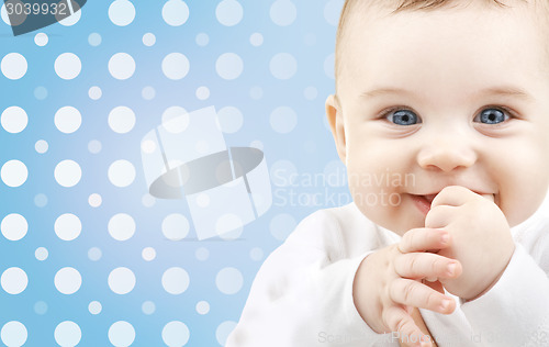 Image of smiling baby boy face over blue polka dots