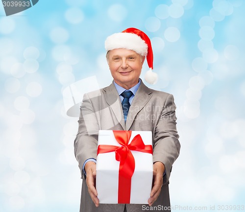 Image of smiling man in suit and santa helper hat with gift