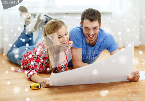 Image of smiling couple with  blueprint at home