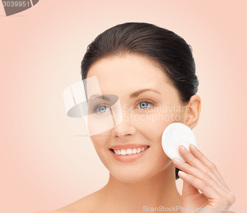 Image of smiling woman cleaning face skin with cotton pad